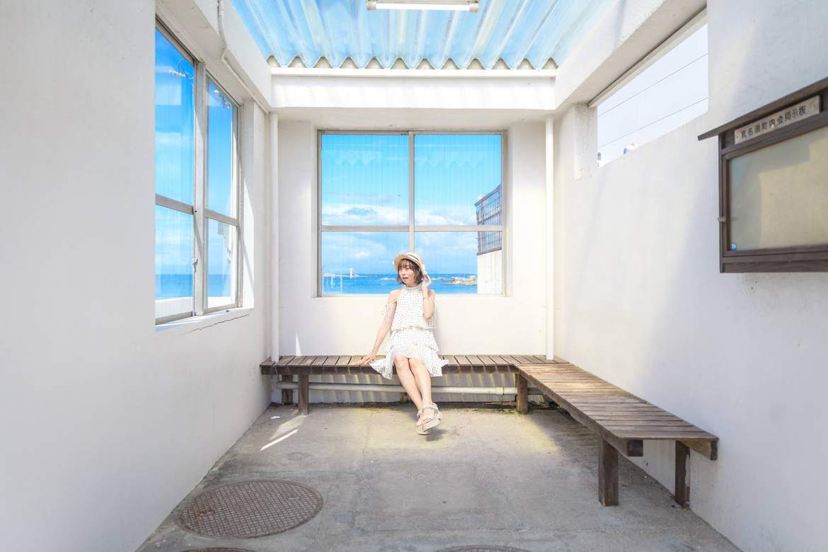 海の見える待合所に座る女性