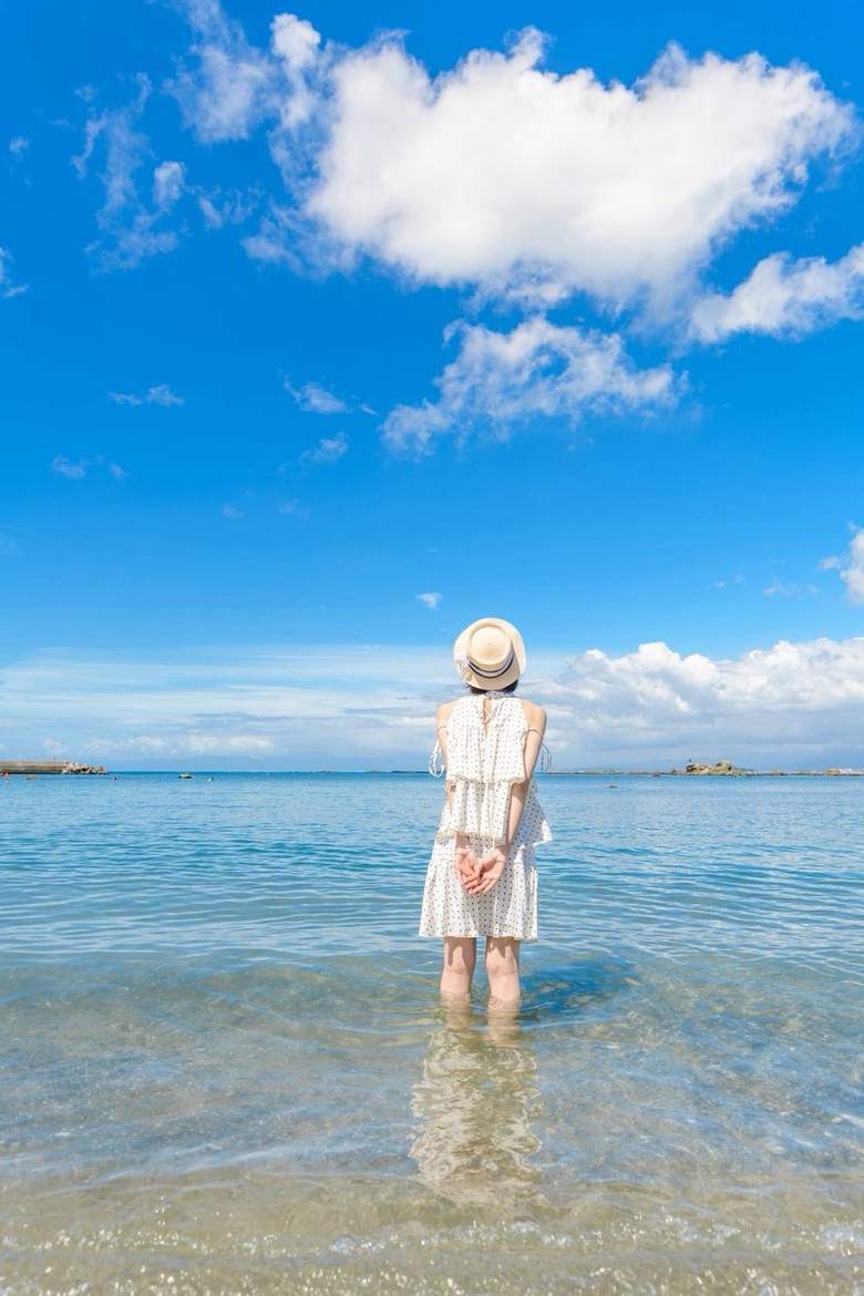 海に立つ女性の後ろ姿