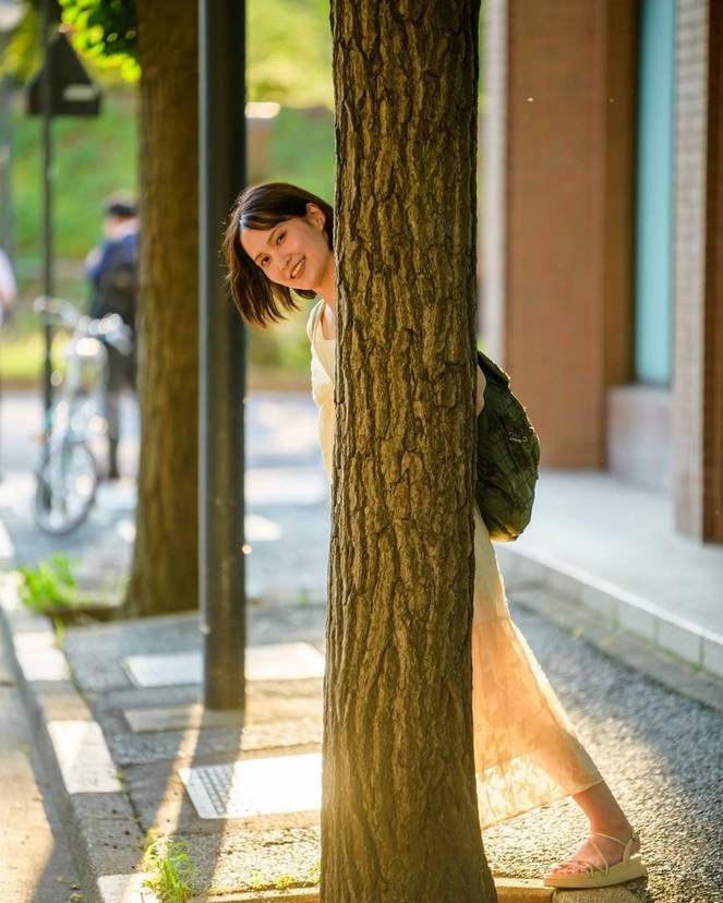街路樹の陰から覗く女性
