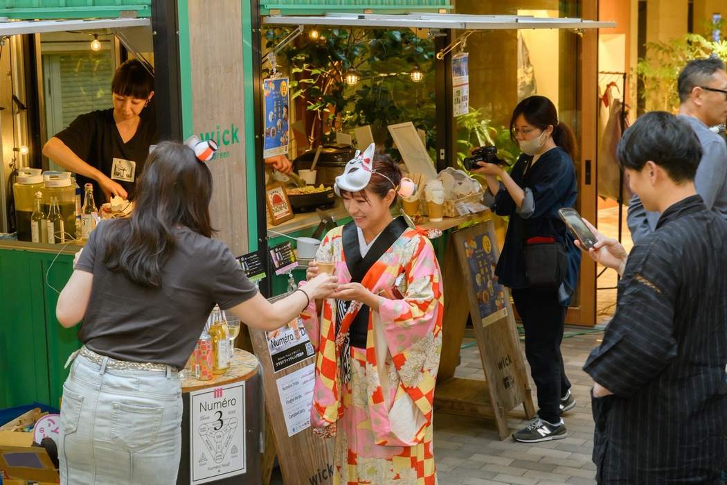 狐面をつけた着物姿の女性と出店