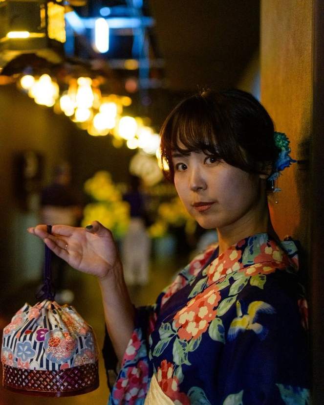提灯の灯りの下に立つ浴衣の女性