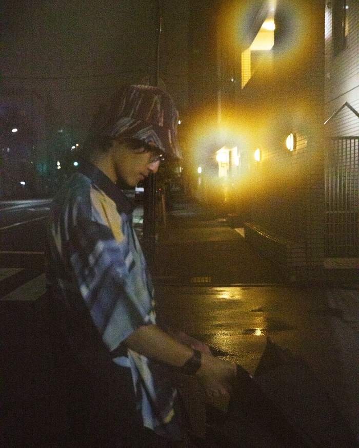 雨の夜の街に座る男性